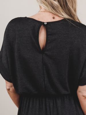 Black dress with open back worn by a person on a neutral background