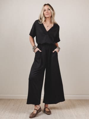 Woman wearing a black jumpsuit against a plain background