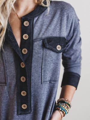 Close-up of a person wearing a black button-up shirt with a neutral background