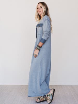 Woman wearing a long denim dress against a white background