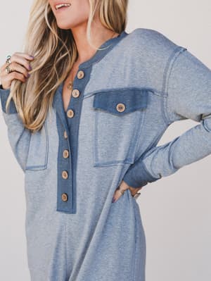 Woman wearing a blue denim dress with button details on a plain background