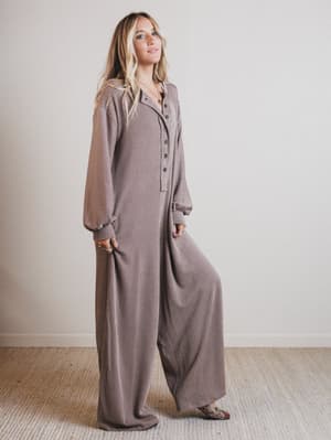 Woman wearing a brown jumpsuit standing against a plain background