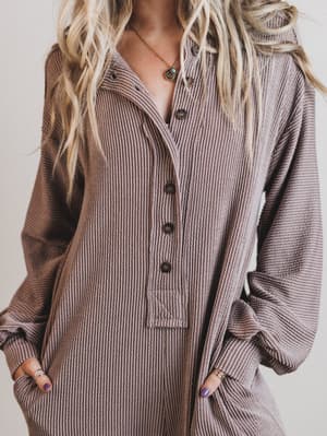 Person wearing a ribbed brown jumpsuit with a neutral background