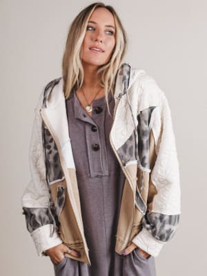 Woman wearing a patterned jacket over a dress against a plain background