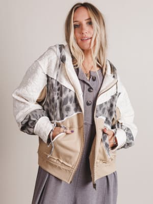 Woman wearing a stylish jacket with a mix of textures and colors on a plain background