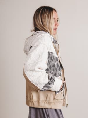 Woman wearing a white quilted jacket with a patterned panel on a plain background