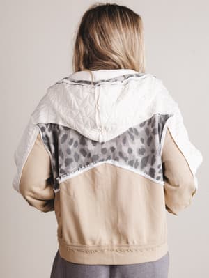 Person wearing a beige jacket with a patterned hood against a plain background