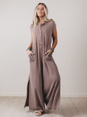 Woman wearing a long brown dress with pockets against a plain background