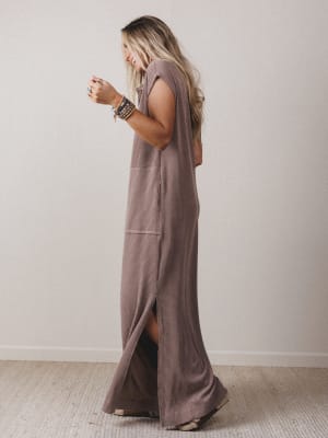 Woman wearing a long brown dress against a plain background
