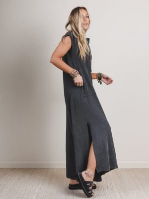 Side view of woman wearing a black and gray patterned sleeveless jumpsuit with leg slits