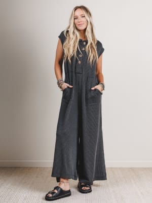Woman wearing a black and gray patterned boho jumpsuit with large buttons.