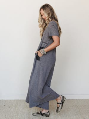 A relaxed, full-length heathered gray jumpsuit styled with striped flats and stacked bracelets — the kind of effortless outfit that looks like you tried just the right amount.