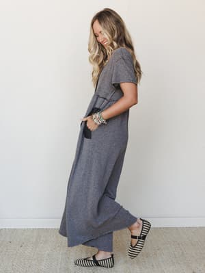 A relaxed, full-length heathered gray jumpsuit styled with striped flats and stacked bracelets — the kind of effortless outfit that looks like you tried just the right amount.