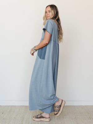 A relaxed, full-length maxi dress in heathered steel blue worn by a model glancing back over her shoulder — easy, lived-in, and styled with platform espadrille sandals and a stack of turquoise bracelets.