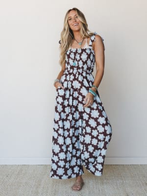 A smocked wide-leg jumpsuit in a bold brown and powder blue retro floral print, styled with turquoise jewelry and flat sandals — the kind of outfit that looks effortless but definitely got a second look.