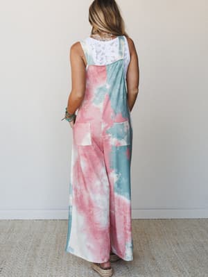 A wide-leg tie-dye overall in cotton-candy pink and seafoam green, shot from the back to show off the relaxed silhouette and lace-back layering detail — the kind of outfit that makes a Saturday feel intentional.