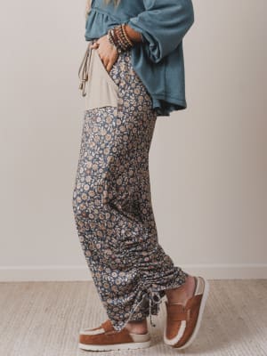 Person wearing floral pants and a blue top against a neutral background