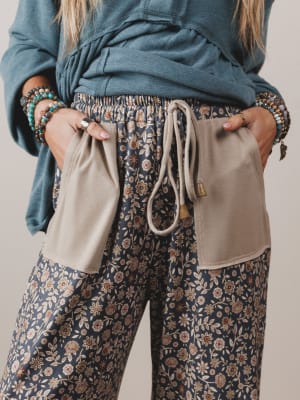 Person wearing floral pants with beige pockets and a blue top against a neutral background