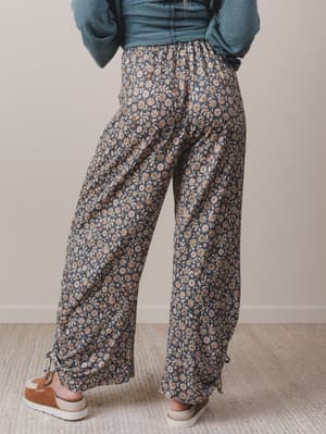 Person wearing floral pants and a blue top against a neutral background
