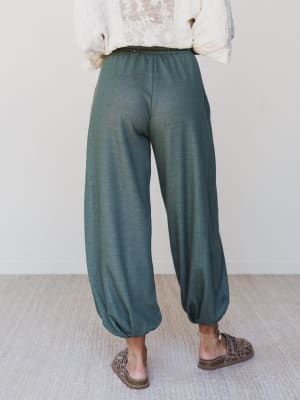 Shot from the back, these relaxed olive jogger pants are styled with a cream lace top and leopard slip-ons — effortlessly cozy with just enough personality to feel intentional.