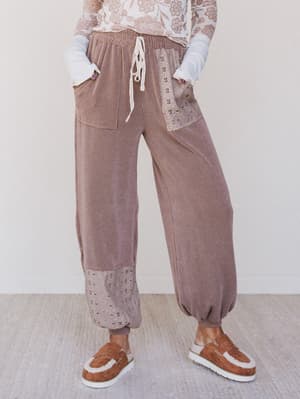 Person wearing brown ribbed pants with lace details on a plain background
