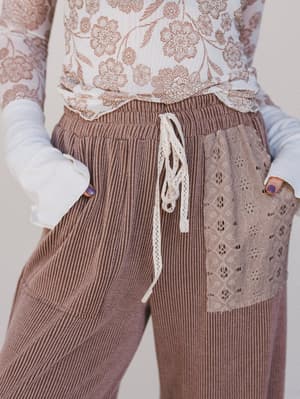 Brown corduroy pants with lace detailing on a plain background