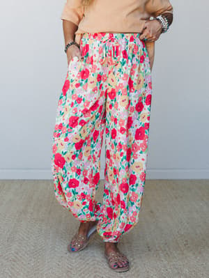 A bold floral jogger in a garden-party-ready red print styled with a soft peach tee and studded sandals — relaxed in shape but full of personality.