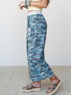 Wide-leg camo pants in a blue-toned army green colorway styled with a cropped textured top and platform espadrille sandals — the kind of effortless, slightly unexpected outfit that makes you look like you tried just the right amount.