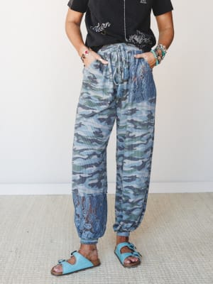 Camo joggers with lace panel inserts styled with a graphic tee and turquoise sandals — the kind of outfit that looks intentional without trying too hard.