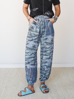 Camo joggers with lace panel inserts styled with a graphic tee and turquoise sandals — the kind of outfit that looks intentional without trying too hard.