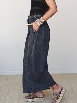 A side-profile shot of wide-leg charcoal pants styled with a black crochet crop top, leopard print espadrille sandals, and a stacked bracelet set — relaxed and expressive, like she threw it together in five minutes and somehow it's perfect.