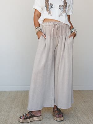 Wide-leg taupe pants with a relaxed drawstring waist styled with a graphic tiger tee, stacked bead bracelets, and espadrille platform sandals — the kind of outfit that looks effortless but was definitely thought about.
