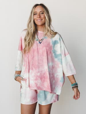 An oversized tie-dye matching set — boxy tee and biker shorts — styled with layered beaded necklaces and stacked bracelets for that effortless, I-just-threw-this-on-and-somehow-nailed-it energy.