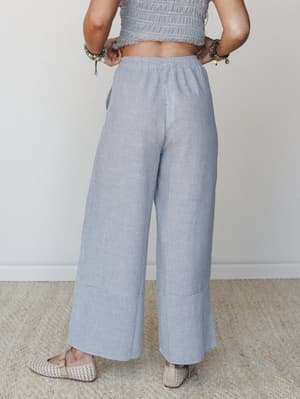 A relaxed wide-leg pant in a fine navy-and-white stripe paired with a matching smocked crop top — the kind of effortless set that looks equally at home on a patio brunch or a slow beach morning.