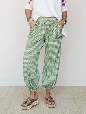 Green gingham jogger pants styled with a white embroidered tee, stacked bracelets, and leopard print platform sandals — relaxed and expressive, the kind of outfit that looks effortless but definitely wasn't an accident.