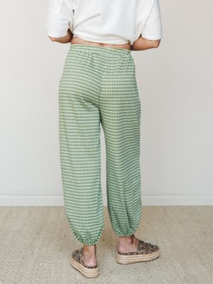Shot from the back, a model wears relaxed green gingham jogger pants paired with a cropped white tee and platform espadrilles — easy, playful, and the kind of outfit that makes a Saturday feel intentional.