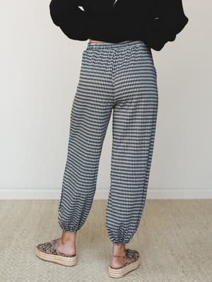 Shot from behind, a model in a black cropped sweater and gingham jogger pants styled with leopard print platform espadrilles — the kind of casual-cool outfit that looks effortless but is clearly thought out.