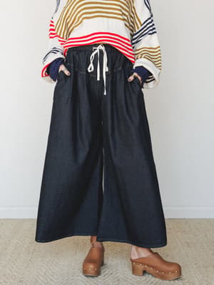 Dark denim wide-leg pants with a relaxed drawstring waist styled with a bold multicolor stripe sweater and brown platform clogs — effortlessly collected, like someone who figured out comfort and cool at the same time.