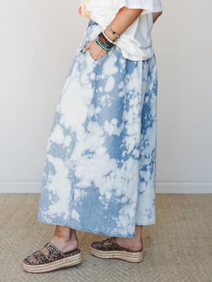 A bleach-dyed denim wide leg pant styled with a casual graphic tee and leopard print platform espadrille slides, shot from the side to show the full sweep of the silhouette — effortlessly cool with a stacked bracelet stack adding a personal touch.