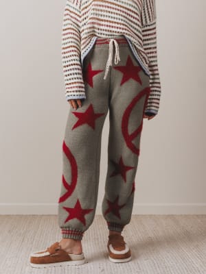 Person wearing a striped sweater and gray sweatpants with red star patterns on a neutral background