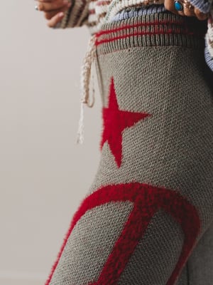 Gray knitted bag with red star design held by a person.