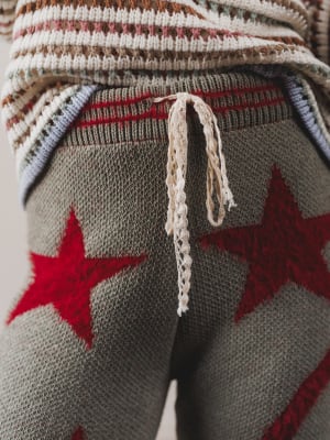 Close-up of a knitted sweater with red star patterns and a drawstring.