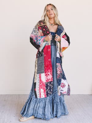 Woman wearing a colorful patchwork kimono over a denim dress with a white background