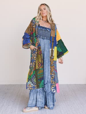 Woman wearing a colorful patterned kimono over a blue dress on a plain background
