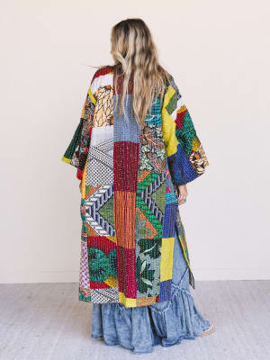 Woman wearing a colorful patchwork coat with a white background