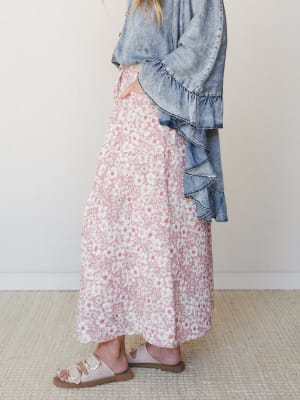 A side-profile shot of a floral maxi skirt in dusty rose paired with a ruffle-trimmed chambray top and buckle sandals — the kind of outfit that looks effortless but was definitely thought about.