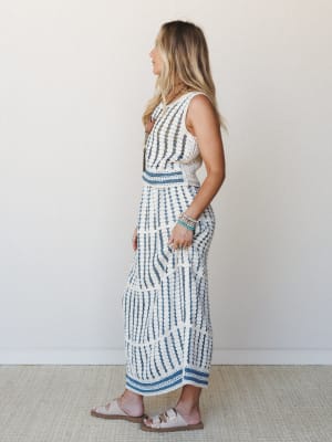 A cream crochet two-piece set with blue stripe accents photographed in profile — effortless and a little artisan, like something you'd find at a coastal market and never stop wearing.