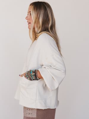 Woman wearing a white jacket with colorful cuffs against a plain background