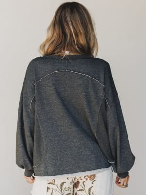 Person wearing a dark gray oversized sweater with a plain background