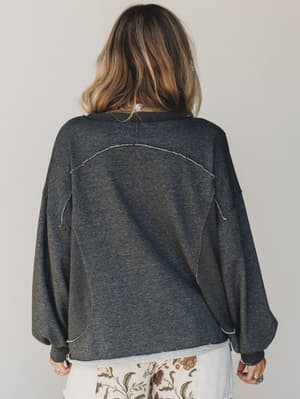 Person wearing a dark gray oversized sweater with a plain background
